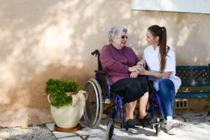 senior woman and nurse talking in assisted living garden. We focus on the important things