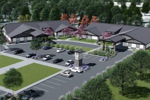 This rendering of The Cottages at Lochsa Falls shows two buildings with covered entrances around a parking lot and surrounded by trees and grass.